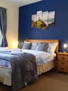 a bedroom with two beds and a blue wall at Oakfield House Bed and Breakfast in Betws-y-coed