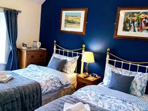 two beds in a room with blue walls at Oakfield House Bed and Breakfast in Betws-y-coed