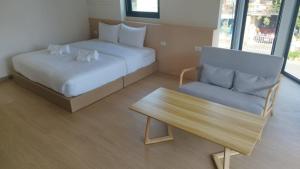 a room with two beds and a bench and a table at บ้านฮา พอชเทล Baan Ha Poshtel in Nan