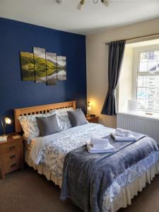 a bedroom with a large bed with blue walls at Oakfield House Bed and Breakfast in Betws-y-coed