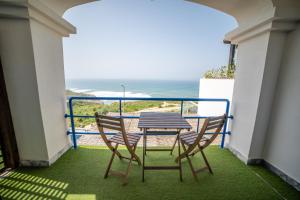 a table and chairs on a balcony with a view of the ocean at Saltline Surf House Ericeira in Ericeira