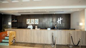 two people sitting at a counter in a hotel lobby at Holiday Inn Abu Dhabi by IHG in Abu Dhabi