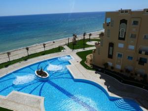 a large swimming pool next to a building and the ocean at Studio with private beach Folla Residence in Akouda
