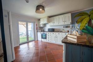a kitchen with white cabinets and a tile floor at Saltline Surf House Ericeira in Ericeira +45 photos