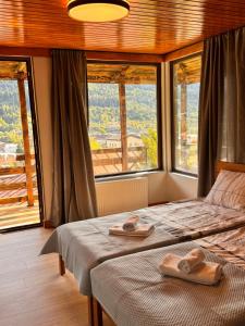 a bedroom with two beds and a large window at Villa Dabderr Mestia in Mestia