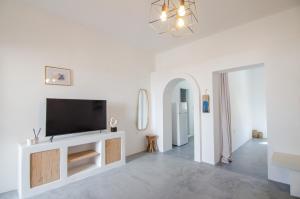 a living room with a flat screen tv on a white wall at Ios Pearls-2 houses in Mylopotas