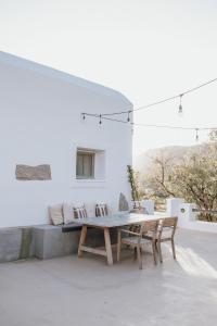 a patio with a table and chairs and a couch at Ios Pearls-2 houses in Mylopotas