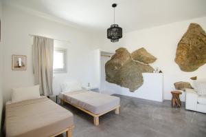 a bedroom with two beds and a rock on the wall at Ios Pearls-2 houses in Mylopotas