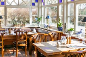 a restaurant with tables and chairs and windows at Haus am Kiel in Ahrenshoop