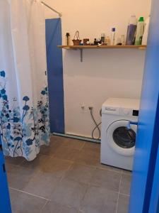 a bathroom with a washing machine and a shower curtain at Amit house in Pardes H̱anna