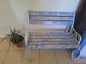 a blue bench sitting in a room with a plant at Amit house in Pardes H̱anna