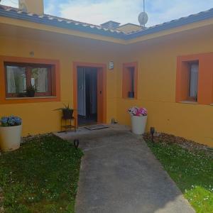 a yellow house with two potted plants in front of it at My Reyna in San Miguel