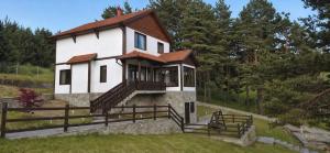a small white house with a porch on a hill at Лунен залив in Dospat