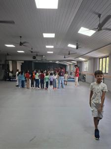 a young boy walking in a large room with a group of people at APKA ECOvillage in Trichūr