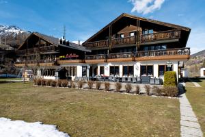 a large wooden building with a lawn in front of it at La Collina Coliving and Coworking in Grächen +48 photos