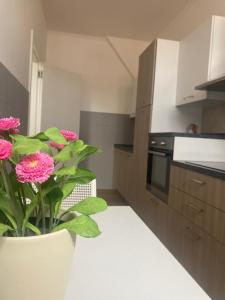 a kitchen with a vase with pink flowers in it at HOMEY I Palazzo Venezian Apartments in Trieste