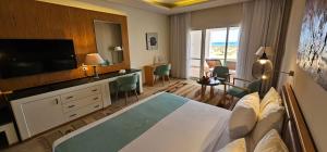 a hotel room with a bedroom with a bed and a television at Lahami Bay Beach Resort in Râs Banâs