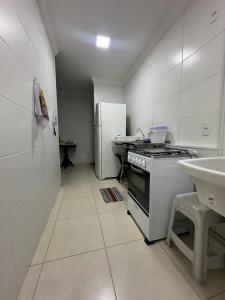a white kitchen with a stove and a refrigerator at Apartamento Melbela IV AP 41 in Espirito Santo Do Pinhal +20 photos