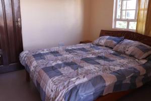 ein Schlafzimmer mit einem Bett, auf dem eine Steppdecke liegt in der Unterkunft Zeph Bnb in Nairobi