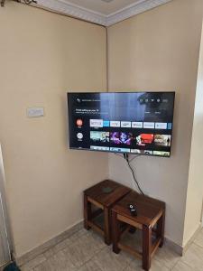 Ein Flachbildfernseher hängt an der Wand, daneben ein Tisch. in der Unterkunft Zeph Bnb in Nairobi
