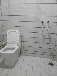 a bathroom with a toilet in a white tiled wall at La vie Livings Only For Female in Noida
