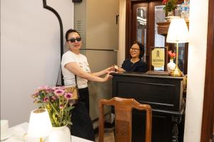 a woman standing in front of a mirror next to a piano at Maison Julie Duong in Hanoi