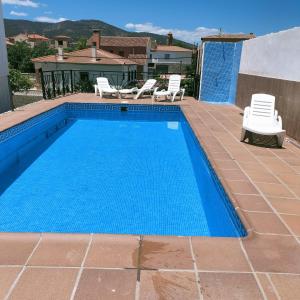 a swimming pool with two lawn chairs and two chairs at Casa Detrés in Cogollos de Guadix