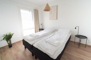 a bedroom with a bed with white sheets and a window at Joutsen Apartments in Rovaniemi