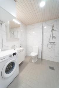 a white bathroom with a washing machine in it at Joutsen Apartments in Rovaniemi