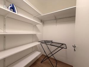 a walk in closet with white shelves and a black stand at Lumi Glow Apartments in Rovaniemi