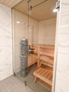 a sauna with a wooden bench and a shower at Lumi Glow Apartments in Rovaniemi