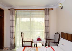 a bedroom with a table and chairs and a window at Premier motel in Bushenyi