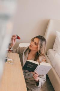 a woman sitting at a table reading a book at Dunetton - self check-in hotel in Klaipėda