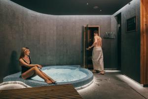 a woman sitting in a hot tub in a bathroom at Dunetton - self check-in hotel in Klaipėda