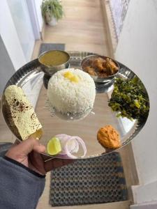 a person holding a tray with rice and food on it at The Boho Darjeeling in Darjeeling +28 photos