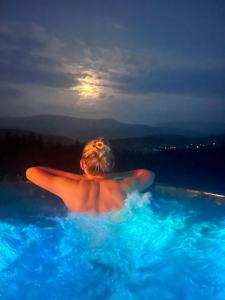 a person in a swimming pool at night at Ovis Homes I Gorąca balia - Widok na góry - 8 osób - Komfortowy domek in Zawoja