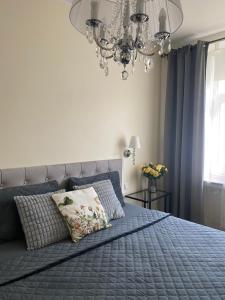 a bedroom with a blue bed with a chandelier at Compass apartment in Tallinn