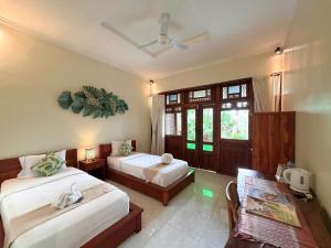 a bedroom with two beds and a table and a window at Mirah Guest House in Tampaksiring +99 photos