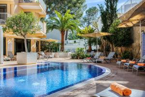 ein Pool in einem Hotel mit Liegestühlen und Sonnenschirmen in der Unterkunft Hotel Morlans in Paguera