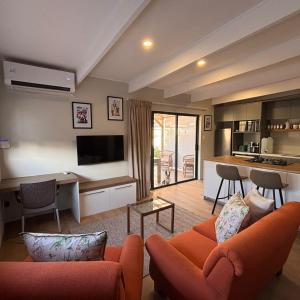 a living room with two orange couches and a kitchen at Bonnie Doon Luxury Studio in Bunkers Hill