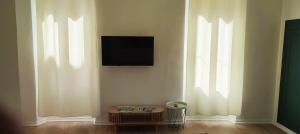 a living room with a tv on a wall with windows at Studio à 5 minutes des Musées in Grasse
