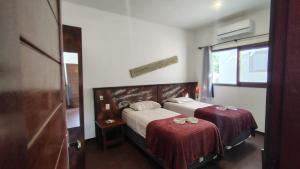 a bedroom with two beds with red sheets and a window at Country Club Pititinga in Pititinga