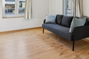 a couch in a living room with a wooden floor at FENUS SGT01 moderne Ferienwohnung in Grabs