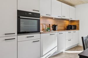 a kitchen with white cabinets and a black oven at FENUS SGT01 moderne Ferienwohnung in Grabs
