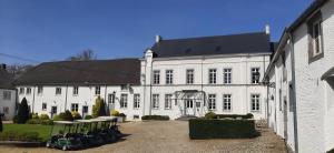 a large white building with chairs in front of it at Hotel Golf de Pierpont in Bons Villers