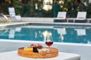 a tray of food and a glass of wine next to a pool at Villa Alexandra by Sweett in Cannes