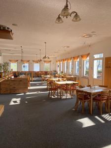 a dining room with tables and chairs and windows at Zum Schlossgarten in Ralswiek