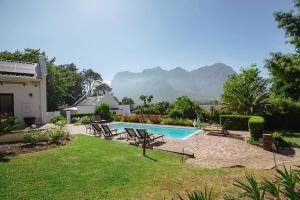Ein Swimmingpool in einem Garten mit Bergen im Hintergrund in der Unterkunft Hemelberg in Stellenbosch