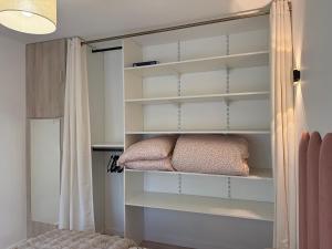 a closet with white shelves and a pillow at Le Refuge Douillet à 10min de Disneyland avec Parking Privé et Belle terrasse vue sur Jardin in Coupvray