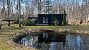 a small cabin in the woods next to a pond at Māja pie Ziedu laivas in Plieņciems